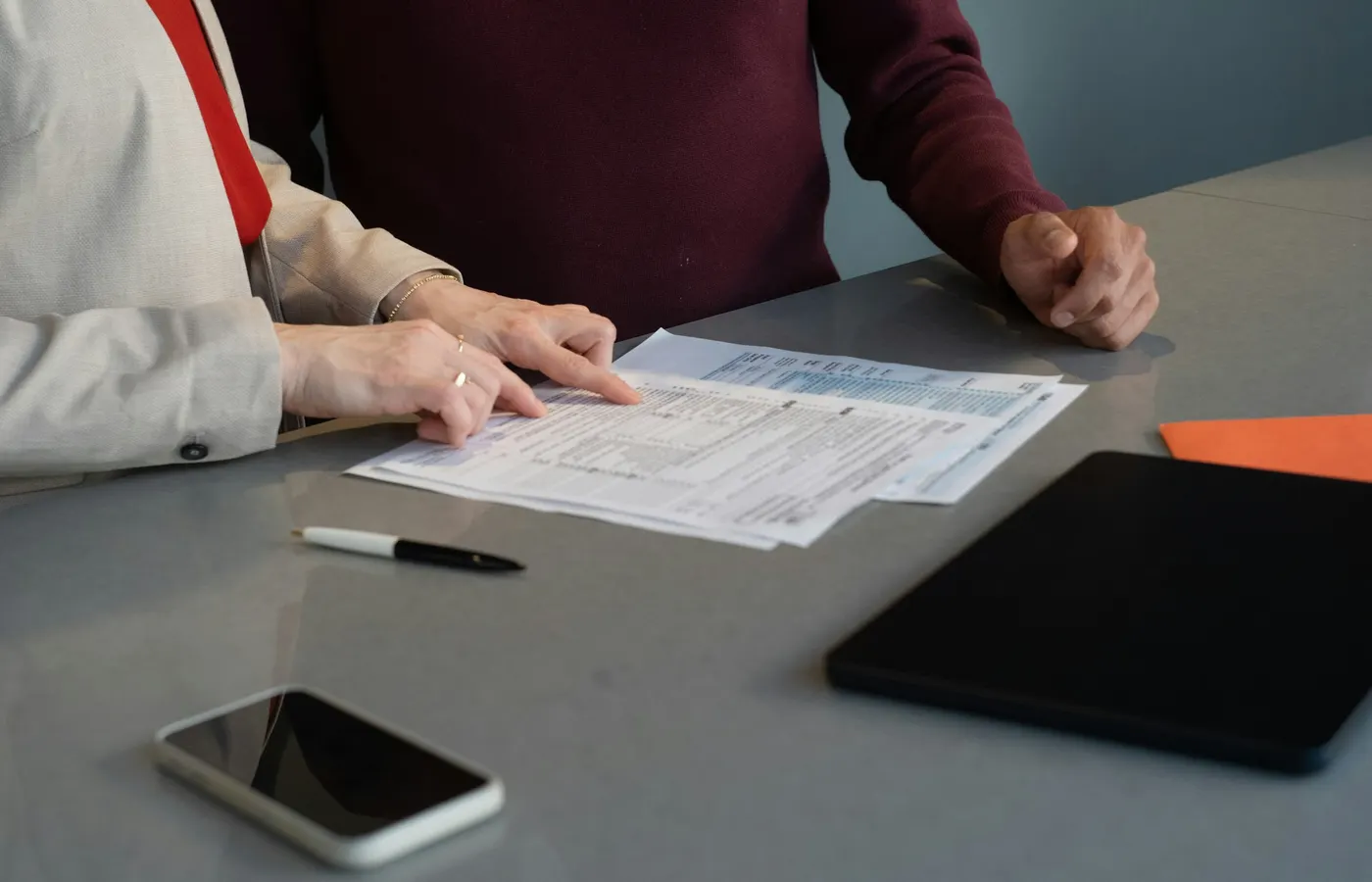 Two professionals reviewing detailed documents together at a conference table